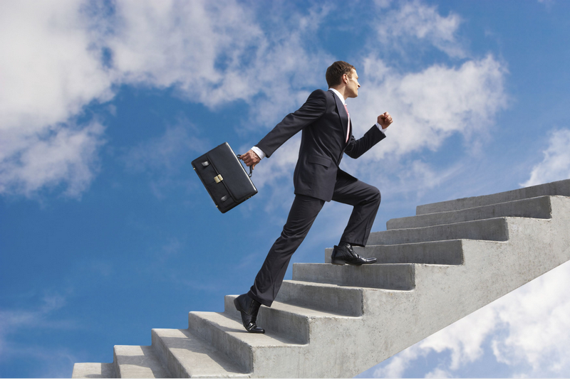 A businessman climbs a concrete staircase toward the sky, holding a briefcase.