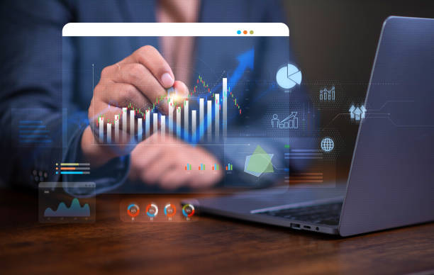 A person analyzing financial graphs on a holographic screen beside a laptop, illustrating tech-driven SME support.