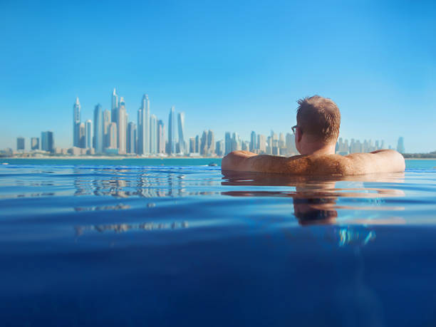 A man relaxes in an infinity pool overlooking the Dubai skyline, representing a lifestyle attainable with a Dubai residence visa.