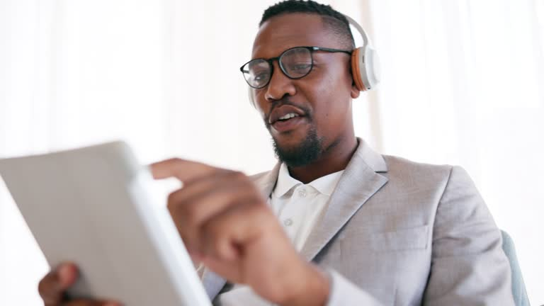 Business professional in a suit and headphones using a tablet, representing tech industries in DMCC Dubai.