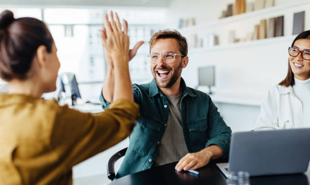 Business partners celebrate with a high five in a modern office, symbolizing success in company registration in Dubai.